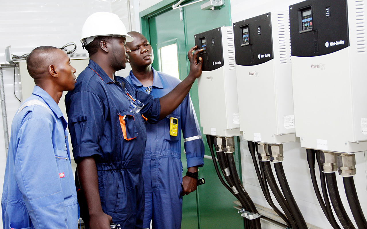 A group of petrochemical technicians looking at a control panel